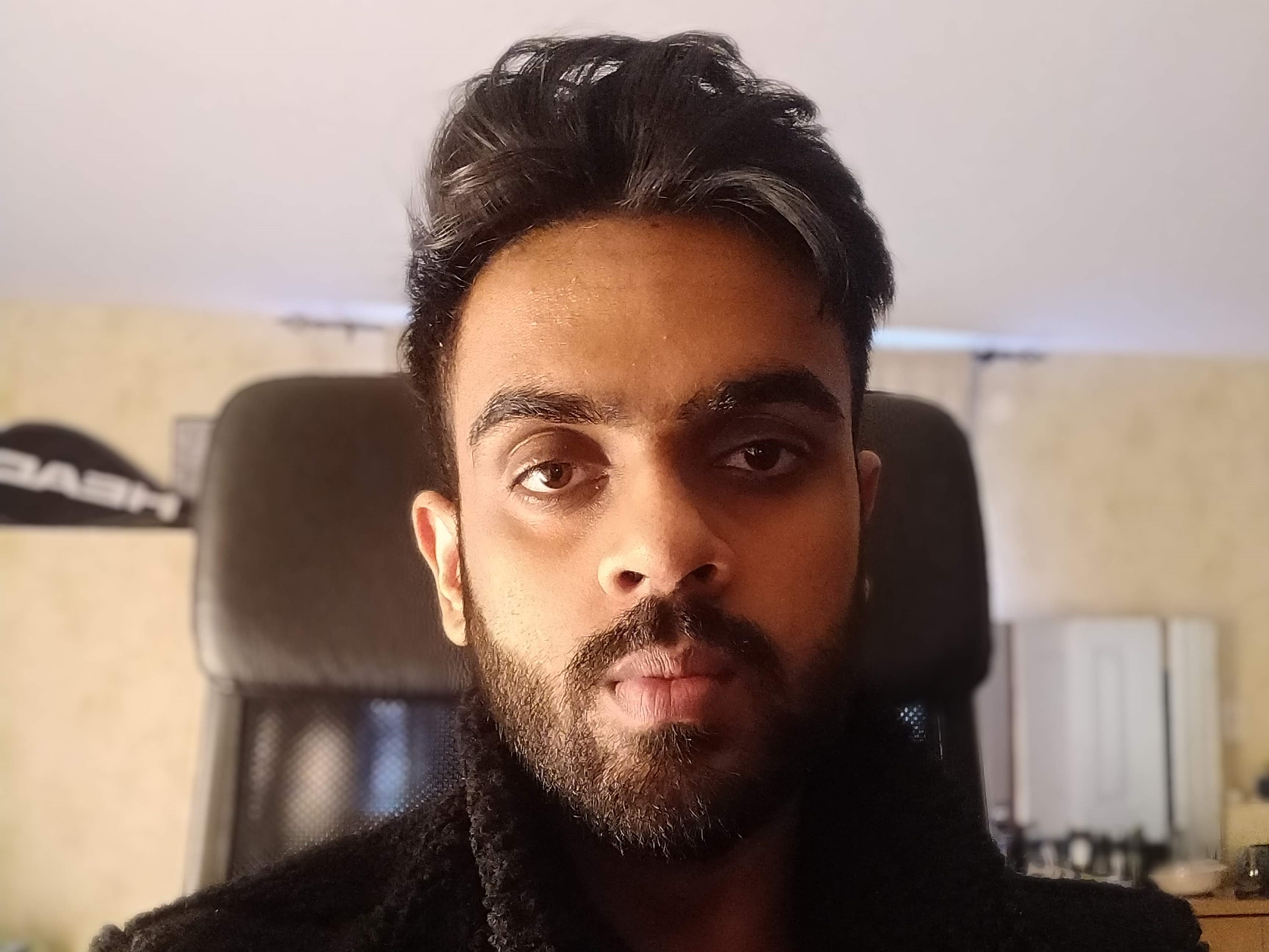Aryamann Verma portrait on chair in black jacket.